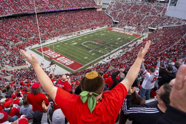 An Ohio State fan wearing a buckeye nut hat cheers on the Best Damn Band in the Land as they perform "Script Ohio" in Ohio Stadium